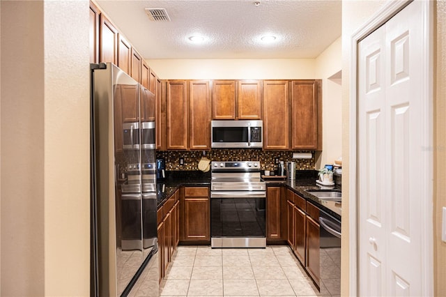 kitchen with visible vents, backsplash, dark countertops, stainless steel appliances, and light tile patterned flooring