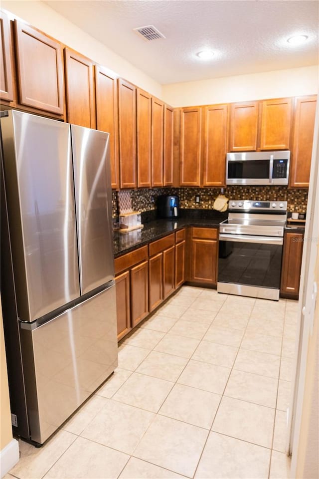 kitchen with tasteful backsplash, light tile patterned flooring, visible vents, and appliances with stainless steel finishes