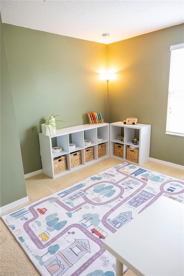 playroom with carpet, baseboards, and a textured ceiling