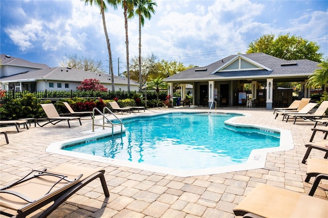 pool with a patio and fence