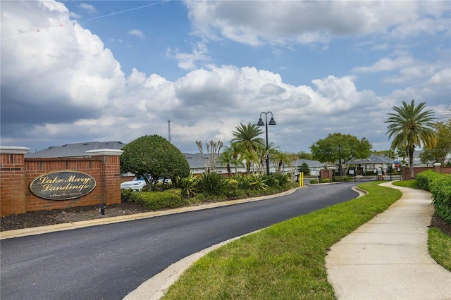 view of road with street lights, a gated entry, a residential view, curbs, and sidewalks