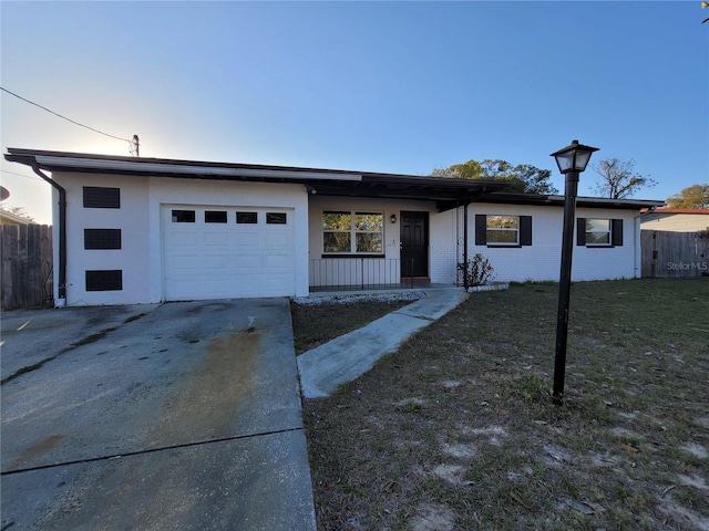 view of front of house featuring a garage, brick siding, fence, driveway, and a front yard