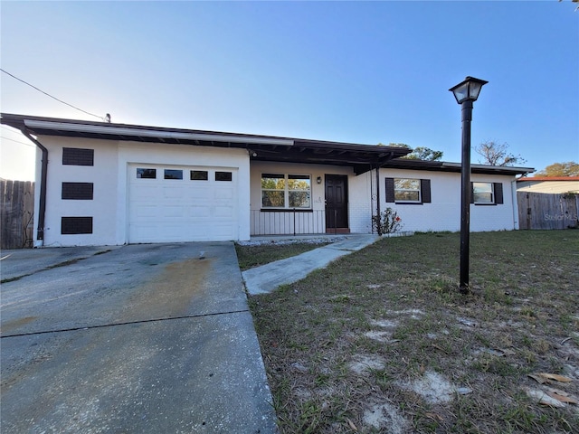 view of front facade featuring a garage, concrete driveway, fence, and a front lawn