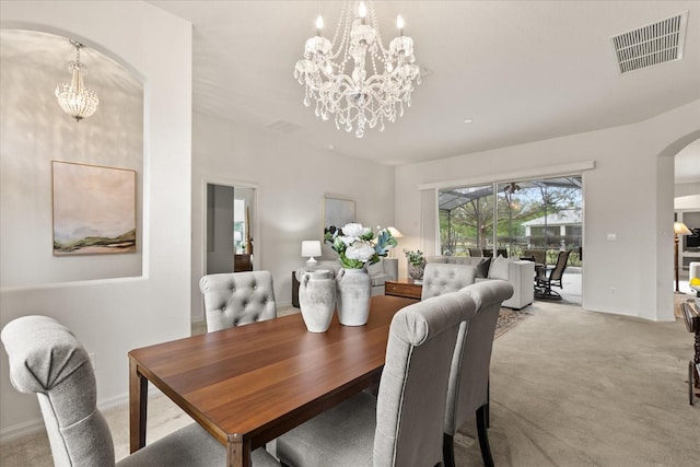 carpeted dining room featuring arched walkways, baseboards, visible vents, and an inviting chandelier