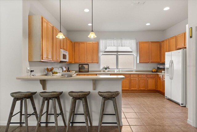 kitchen featuring a breakfast bar area, light countertops, visible vents, white appliances, and a peninsula