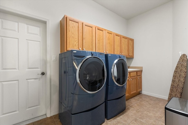 laundry room featuring washing machine and dryer, cabinet space, baseboards, and light tile patterned floors