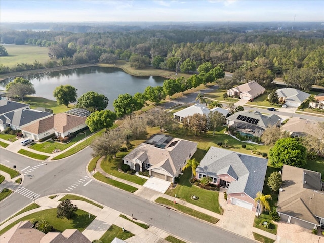 drone / aerial view featuring a water view, a wooded view, and a residential view