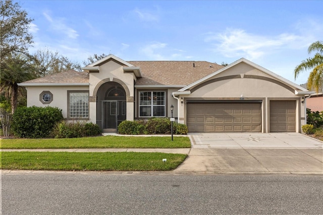 view of front of house featuring a front yard, driveway, an attached garage, and stucco siding