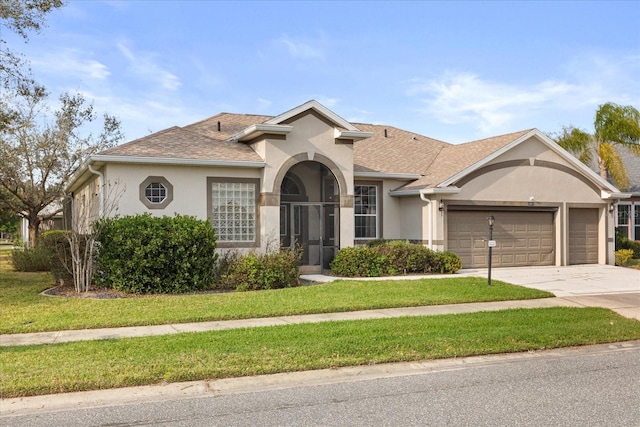 view of front of property featuring driveway, a shingled roof, stucco siding, an attached garage, and a front yard