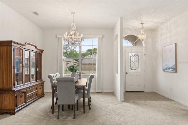 dining room with visible vents, light colored carpet, and a notable chandelier