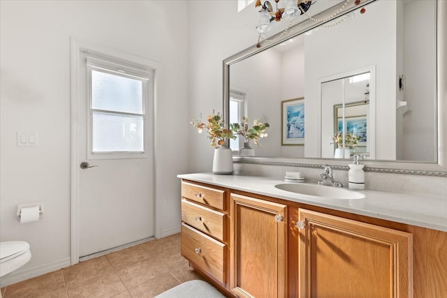 bathroom with toilet, tile patterned flooring, baseboards, and vanity