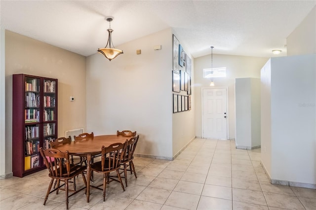 dining space featuring lofted ceiling, a textured ceiling, light tile patterned flooring, and baseboards