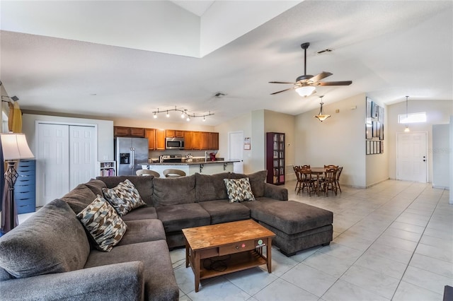 living room featuring a ceiling fan, visible vents, vaulted ceiling, and light tile patterned flooring