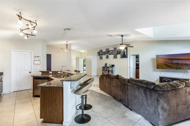 kitchen with open floor plan, stainless steel dishwasher, vaulted ceiling, and a sink