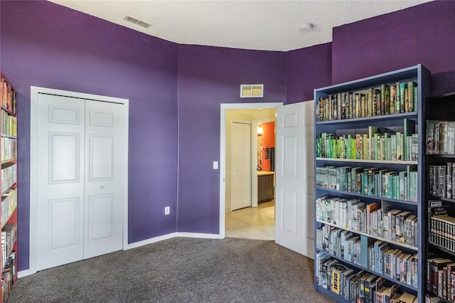 carpeted bedroom with tile patterned flooring, a closet, and visible vents