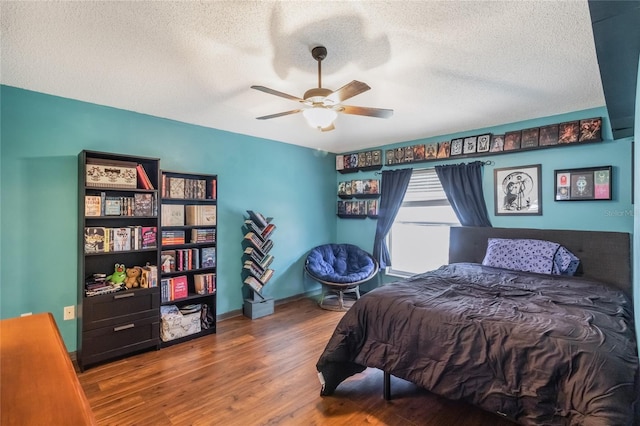 bedroom with a textured ceiling, wood finished floors, a ceiling fan, and baseboards