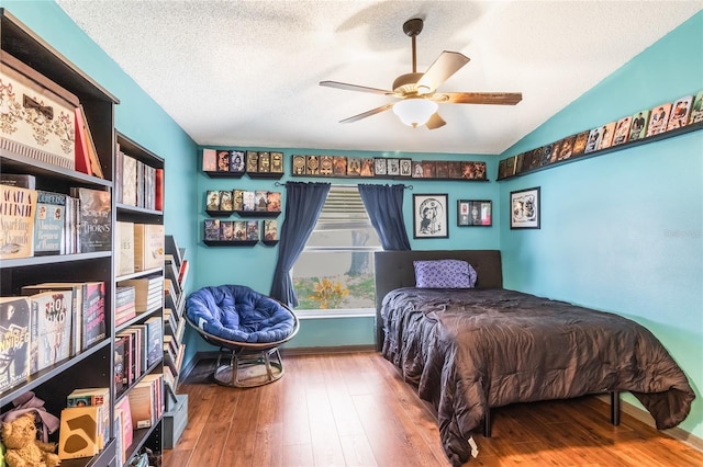 bedroom featuring wood-type flooring, a ceiling fan, vaulted ceiling, and a textured ceiling