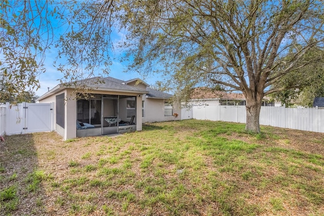 back of house featuring a sunroom, a fenced backyard, a gate, and a yard