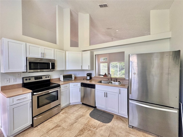 kitchen with visible vents, stainless steel appliances, light countertops, white cabinetry, and a sink