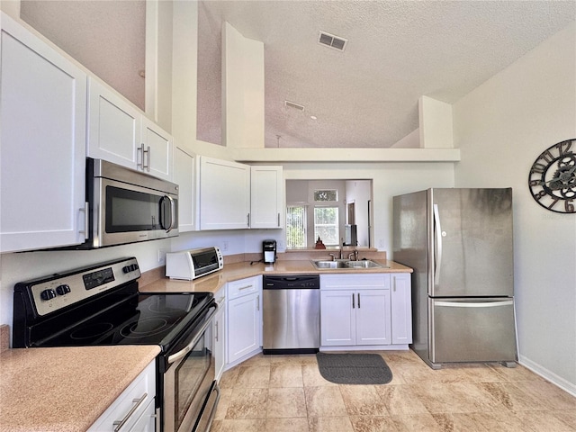 kitchen with stainless steel appliances, light countertops, a sink, and visible vents