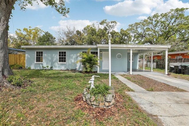 ranch-style house with a carport, concrete driveway, fence, and a front lawn