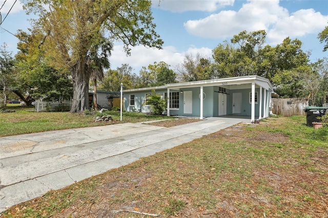 view of front of home featuring a front yard, driveway, an attached carport, and fence