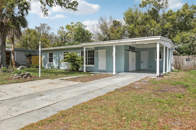 view of front facade with a front yard, driveway, an attached carport, and fence