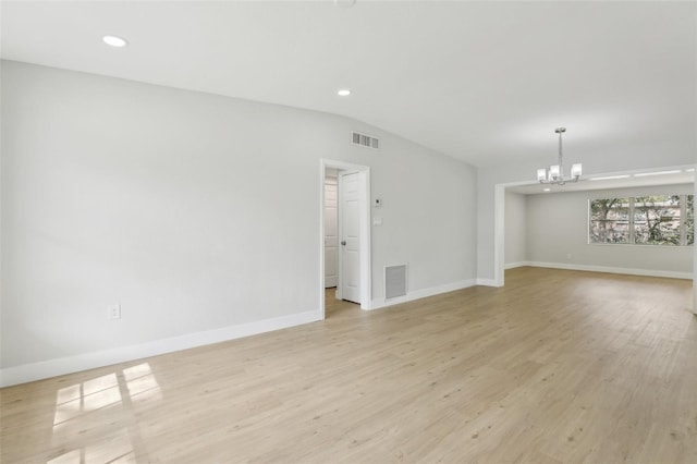 spare room with lofted ceiling, light wood-style flooring, visible vents, and a notable chandelier