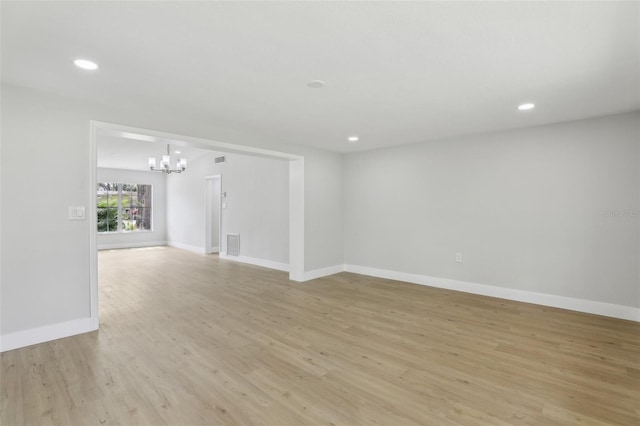 empty room with a chandelier, recessed lighting, baseboards, and light wood-style floors