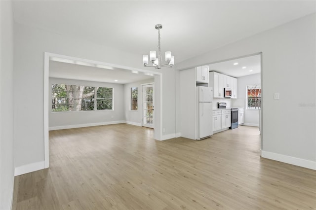 unfurnished living room featuring a wealth of natural light, baseboards, and light wood finished floors