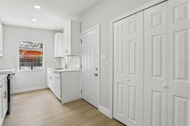 kitchen with dishwasher, light countertops, a sink, and light wood-style floors