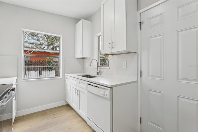 kitchen with baseboards, white dishwasher, light countertops, white cabinetry, and a sink