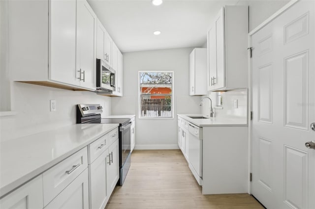 kitchen featuring light countertops, light wood-style flooring, appliances with stainless steel finishes, white cabinets, and a sink