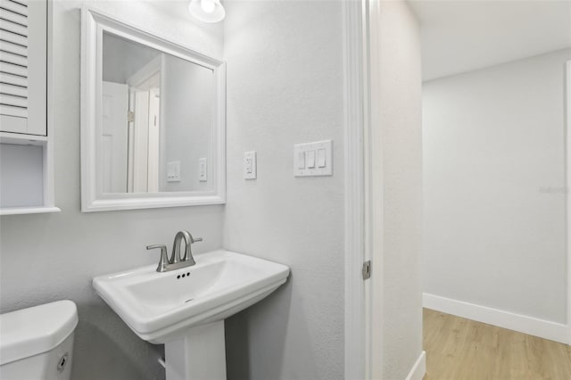 bathroom with a sink, baseboards, toilet, and wood finished floors