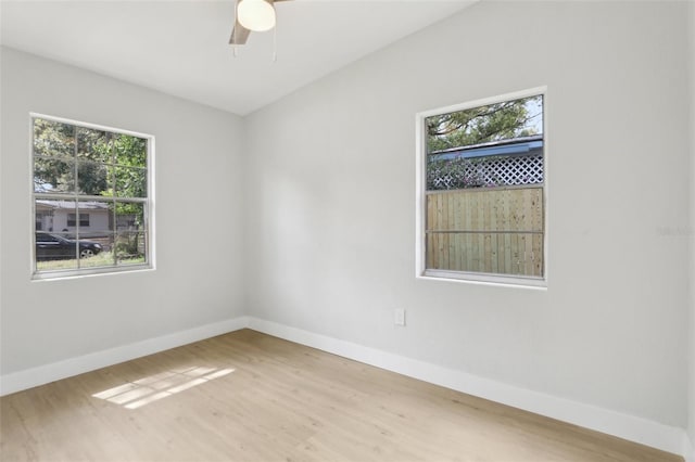 empty room with plenty of natural light, wood finished floors, and baseboards