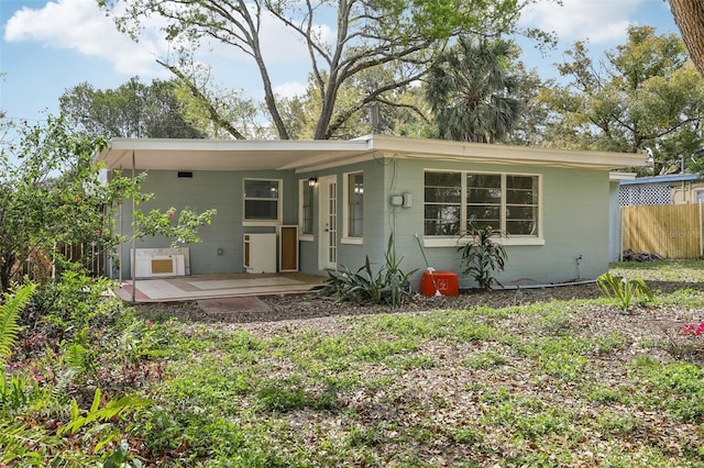 view of front facade featuring concrete block siding and fence