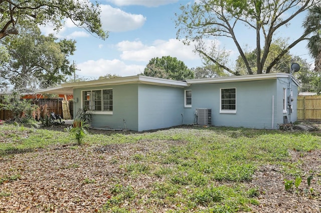 back of property featuring central air condition unit, fence, and concrete block siding