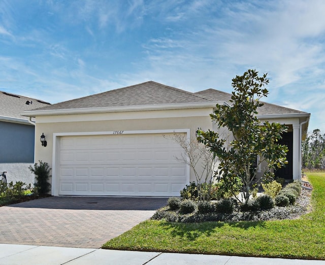 view of front of home featuring an attached garage, a shingled roof, decorative driveway, and stucco siding