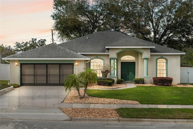 view of front of house featuring a garage, fence, driveway, stucco siding, and a front lawn