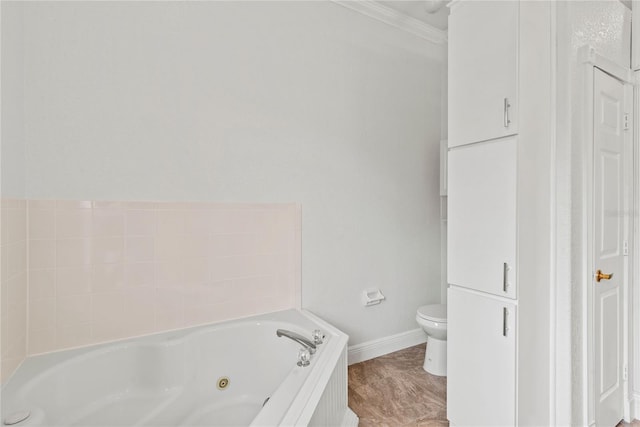 bathroom featuring toilet, baseboards, a tub with jets, and ornamental molding