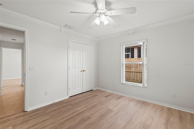 unfurnished bedroom featuring visible vents, baseboards, a closet, light wood finished floors, and crown molding