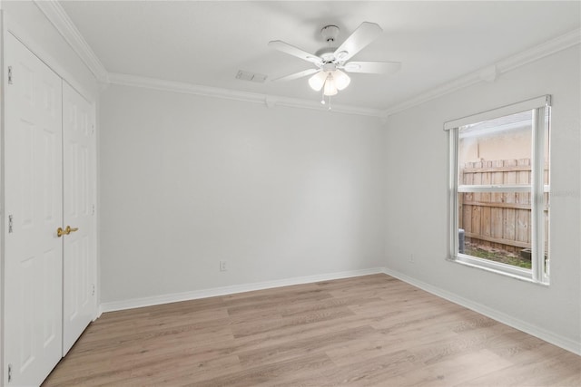 empty room with ornamental molding, visible vents, light wood-style flooring, and baseboards