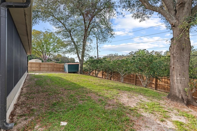 view of yard featuring an outbuilding, a fenced backyard, and a shed