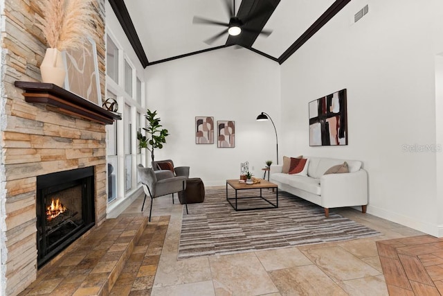 living area with baseboards, ceiling fan, crown molding, a fireplace, and high vaulted ceiling