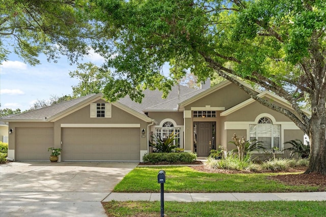 view of front facade with a garage, concrete driveway, and stucco siding