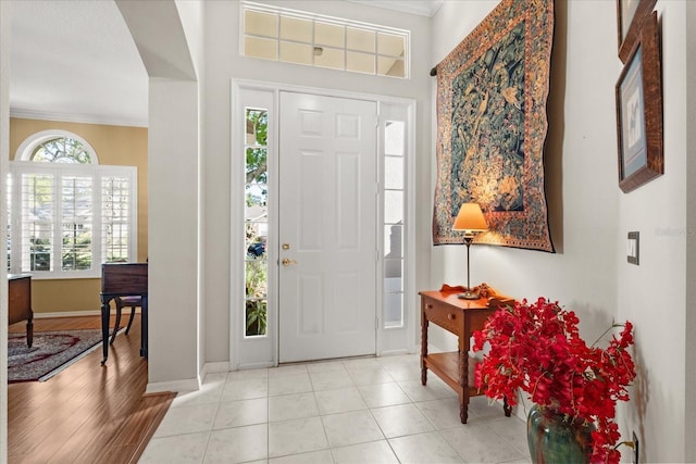 entryway with baseboards, ornamental molding, and light tile patterned flooring