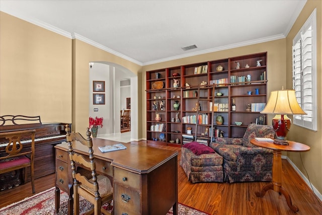 home office with visible vents, arched walkways, a wealth of natural light, and wood finished floors