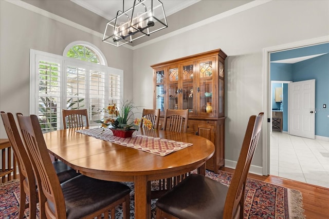 dining room with light wood finished floors, a notable chandelier, baseboards, and crown molding