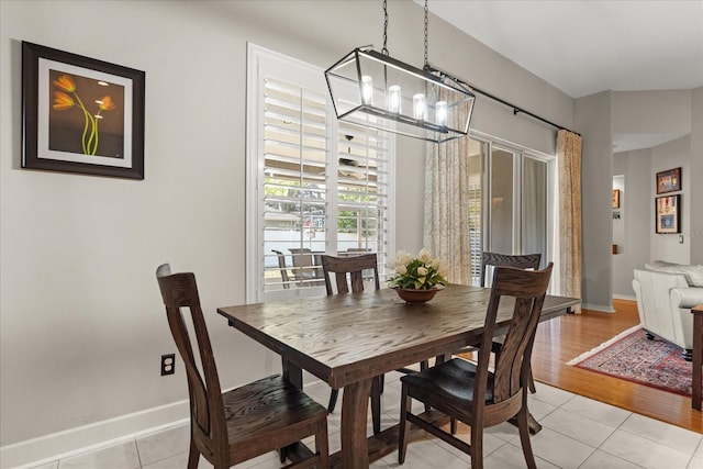 dining space with baseboards, a notable chandelier, and light tile patterned flooring