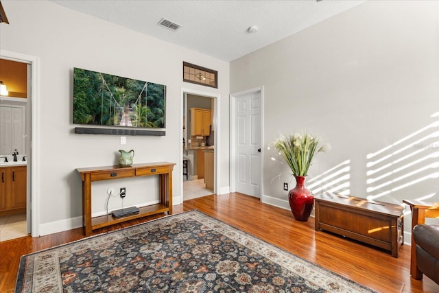 interior space featuring visible vents, a textured ceiling, baseboards, and wood finished floors